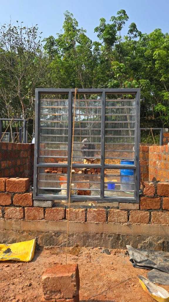 Steel grilled window unit being set into a brick opening on a building site